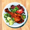 Grilled chicken leg and vegetables on white plate