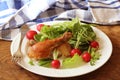 Grilled chicken legs with fresh vegetables on wooden table served on white plate . Dinner background Royalty Free Stock Photo