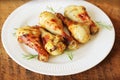 Grilled chicken legs with mustard on wooden table served on white plate with rosemary. BBQ dinner background Royalty Free Stock Photo