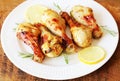 Grilled chicken legs with mustard on wooden table served on white plate with rosemary and lemon. BBQ dinner background Royalty Free Stock Photo