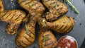 Grilled chicken legs and wings with red sauce on a black stone surface Royalty Free Stock Photo