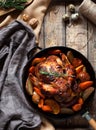 Grilled chicken with potatoes and vegetables in a cast-iron frying pan on a wooden rustic background. Close-up. View Royalty Free Stock Photo