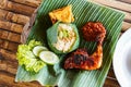 Grilled chicken with red barbecue sauce, vegetables and chili sauce served on banana leaves Royalty Free Stock Photo