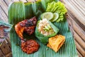 Grilled chicken with red barbecue sauce, vegetables and chili sauce served on banana leaves Royalty Free Stock Photo