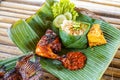 Grilled chicken with red barbecue sauce, vegetables and chili sauce served on banana leaves Royalty Free Stock Photo