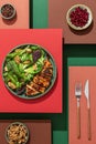 Grilled chicken salad on abstract colorful layered background. Creative food concept. Colorful minimalism