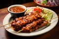 Grilled chicken satay with spicy sauce and salad on wooden table