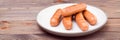 Grilled chicken sausages ready to eat on a plate on a wooden table