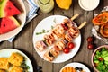 Grilled chicken and vegetable kabobs with a frame of summer picnic food, top view over wood Royalty Free Stock Photo