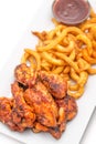 Grilled chicken wings with french fries an tomato sauce on white plate Royalty Free Stock Photo