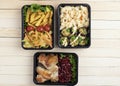 Ready meal to eat, containers with fried chicken wings and raw vegetables on rustic background, cherry tomato and micro greens