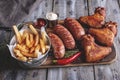 Grilled chicken wings,sausages french fries, white and red sauce on a wooden surface. view on top Royalty Free Stock Photo