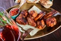 Grilled chicken wings, tomato sauce, greens and glass of wine on a plate.