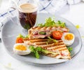 Grilled club sandwich panini with ham, tomato, cheese, avocado and cup of coffee. Royalty Free Stock Photo