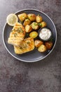 Grilled cod fish with baked jacket potatoes, cream sauce and lemon close-up in a plate. Vertical top view Royalty Free Stock Photo