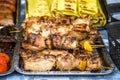 Grilled corn with assorted meat skewers or kebabs fresh from cooking over a barbecue fire on display at a market, buffet or