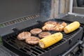 Grilled corn, chicken, and burgers cooking on a backyard bbq grill Royalty Free Stock Photo