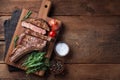 Grilled cowboy beef steak, herbs and spices on a rustic wooden background. Top view with copy space for your text