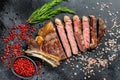 Grilled cowboy or ribeye beef steak with herbs and spices. Black background. Top view