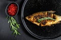 Grilled crucian carp on a white plate. River organic fish. Black background. Top view Royalty Free Stock Photo