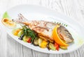 Grilled dorado fish with baked vegetables and rosemary on plate on wooden background close up. Royalty Free Stock Photo
