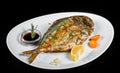 Grilled dorado fish with greens and lemon on black background isolated.