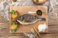 Grilled dorado fish with lemon and potato wedges on wooden board and glass of beer on wooden table Royalty Free Stock Photo