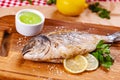 Grilled dorado fish with lemon and sauce on wooden board. Royalty Free Stock Photo