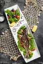 Grilled dorado fish and salad on a white plate on a dark background. top view. place for text Royalty Free Stock Photo