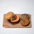 Grilled double or triple meat burger with tomatoes, onion and lettuce on parchment paper. Set of ingredients for super