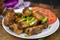 Grilled fat pork ribs on a bone served on a plate with vegetables. Roasted barbeque meat on dark background Royalty Free Stock Photo