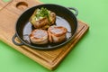 Grilled fillet mignon at the restaurant. Medallion steak dish with baked stuffed potato served in a frying pan Royalty Free Stock Photo