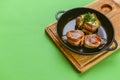 Grilled fillet mignon at the restaurant. Medallion steak dish with baked stuffed potato served in a frying pan Royalty Free Stock Photo