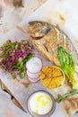 Grilled fish Dorado with lemon and herbs on a white background top view.