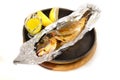 Grilled fish in foil uith lemon juice sauce in black pan on wood Royalty Free Stock Photo