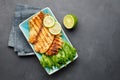 Grilled fish with fresh herbs and lime in a rectangular blue plate.