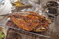 Grilled fish. Placed on a burnt flops, on a cutting board on a wooden table Royalty Free Stock Photo