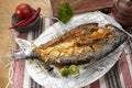 Grilled fish. Placed on a burnt flops, on a cutting board on a wooden table Royalty Free Stock Photo