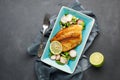 Grilled fish sea bass with fresh herbs, radish and lime in a rectangular blue plate.