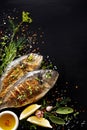 Grilled fish, sea bream with additions, herbs, olive oil, spices on a black background. Composition in the bottom left corner.