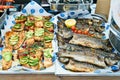 Grilled fish with small tomatoes, herbs, avocado and lemon on a metal deco. Outdoor barbecue fish. Two fish dishes