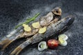 Grilled fish with spices, vegetables and herbs on slate background ready for eating. Royalty Free Stock Photo