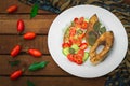 Grilled fish steak with vegetables on plate: tomatoes, microgran, cucumber, tasty and healthy dinner. Wooden rustic background. To Royalty Free Stock Photo