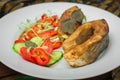 Grilled fish steak with vegetables on plate: tomatoes, microgran, cucumber, tasty and healthy dinner. Wooden rustic background. To Royalty Free Stock Photo