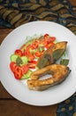 Grilled fish steak with vegetables on plate: tomatoes, microgran, cucumber, tasty and healthy dinner. Wooden rustic background. To Royalty Free Stock Photo