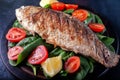 Grilled fish with tomatoes, spinach on a wooden board. Delicious and light dinner Royalty Free Stock Photo