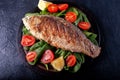 Grilled fish with tomatoes, spinach on a wooden board. Delicious and light dinner Royalty Free Stock Photo