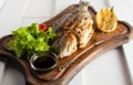 Grilled fish & x28;Dorado& x29; on a wooden board with lemon, salad, sauce and cherry tomatoes Royalty Free Stock Photo