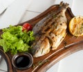 Grilled fish & x28;Dorado& x29; on a wooden board with lemon, salad, sauce and cherry tomatoes Royalty Free Stock Photo