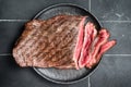 Grilled Flap or Flank Steak, sliced on a plate. Black background. Top view Royalty Free Stock Photo